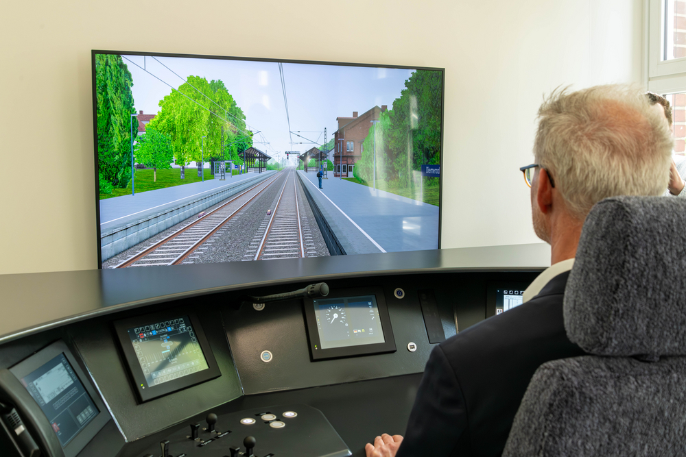 Am Simulator für künftige Zugführer vor der Schaltkonsole mit Blick auf die Zugstrecke 